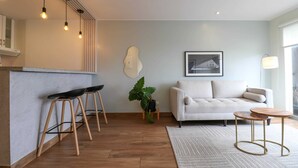 A modern living room with a sofa, a small coffee table, and a bar area with stools.