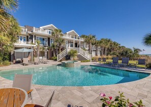 A pool area with a hot tub, lounge chairs, and a staircase leading to a building with balconies.