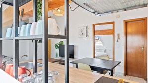 Eine moderne Küche mit Holzarbeitsplatte, einer eingebauten Ablage mit Geschirr und einem Essbereich mit Tisch und Stühlen.