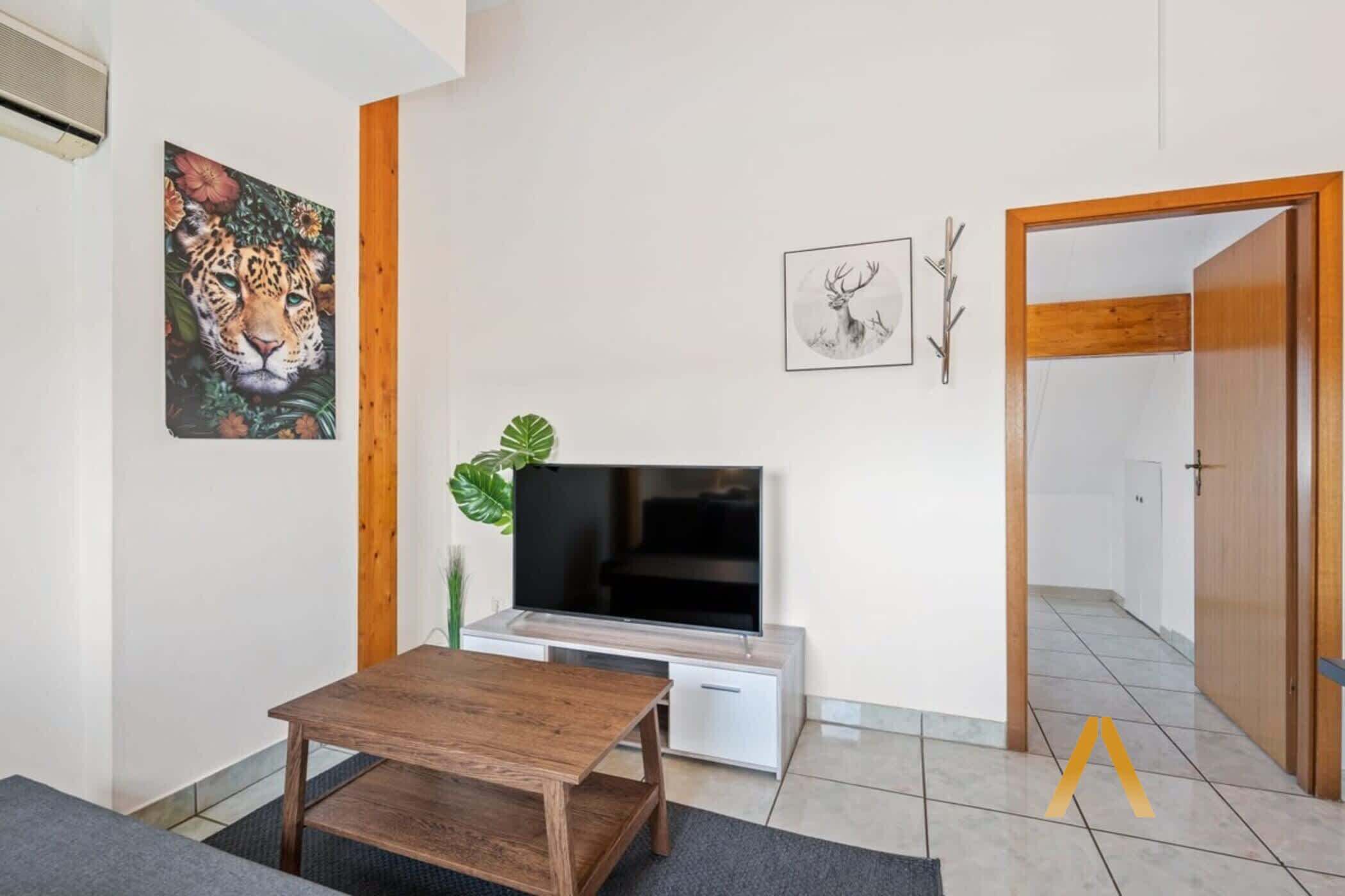Ein Wohnzimmer mit Flachbildfernseher, Holzmöbeln und Wandbildern.