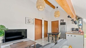 Ein kompakter Wohnbereich mit Sofa, Fernseher, Esstisch und Küchenzeile.