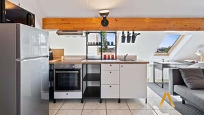 Eine kleine Küche mit Kühlschrank, Backofen und Holzboden.