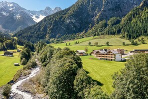 A mountain landscape with a river, houses, and a large building with multiple rooms. - Brandnerhus (Brand)