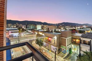 Un paisaje urbano al anochecer, con edificios, una calle y una cordillera al fondo.
