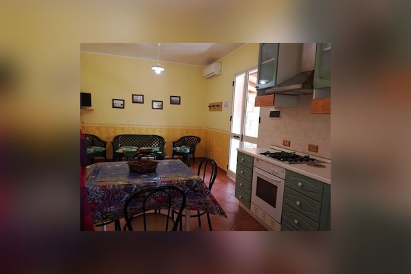 A compact kitchen with a dining area, featuring a stove, cabinets, and a table with chairs.