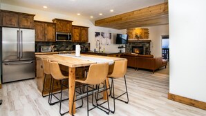 Een moderne keuken met houten kastjes, roestvrijstalen apparatuur en een centraal eiland met barstoelen.