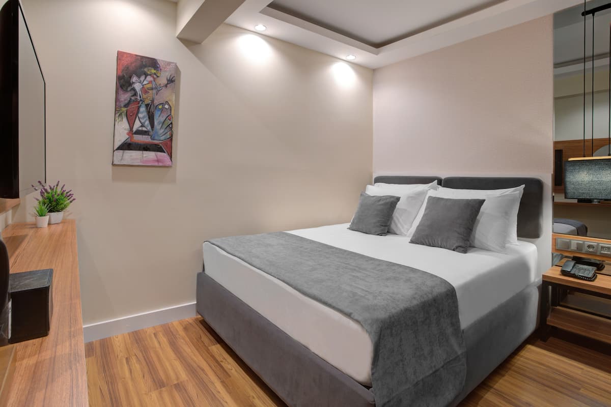 A modern bedroom with a large bed, bedside table, and a painting on the wall.