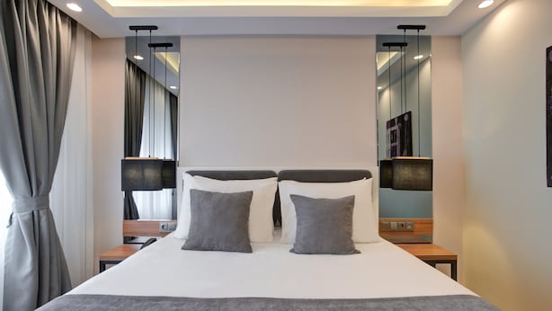 A modern hotel room with a large bed, two bedside tables, a nightstand, a mirror, and a curtain. - Depiero Hotel Karaköy (Istanbul)