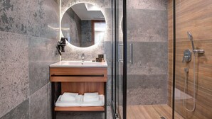A modern bathroom with a glass-enclosed shower, a wooden vanity with a sink, and a large mirror. - Depiero Hotel Karaköy (Istanbul)