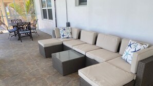 A sectional sofa with a glass coffee table and matching ottomans, a dining set, and a view of the outdoors. - Beautiful House on the beach. Come and enjoy your paradise vacation! (George Town)