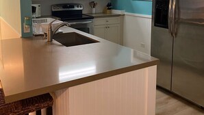 A kitchen with a central island, stainless steel appliances, and light blue walls. - Beautiful House on the beach. Come and enjoy your paradise vacation! (George Town)