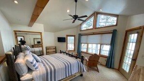 Un dormitorio con una cama grande, un ventilador de techo y varias ventanas.