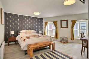 A bedroom with a bed, bedside tables, a wooden bench, a rug, and a window with curtains. - Old Quebec Penthouse | River Views & Balcony (Quebec City)