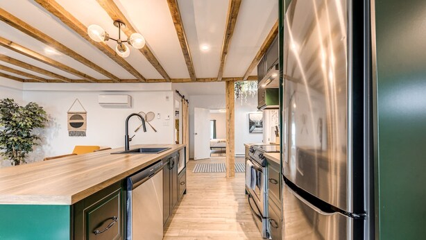Una cocina moderna con vigas de madera, un refrigerador de acero inoxidable y una encimera de madera.