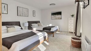 A bedroom with two beds, a white dresser, a wall-mounted lamp, and framed artwork. - Unique and Sunny Top Floor Old Quebec Gem (Quebec City)