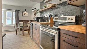 A modern kitchen with a built-in oven, a microwave, and a stainless steel range. - Unique and Sunny Top Floor Old Quebec Gem (Quebec City)