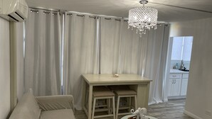 Ein Zimmer mit einer Couch, einem kleinen Tisch mit Tablett und Elefantfigur, einem Schreibtisch mit Stühlen und einer Kristallleuchter.
