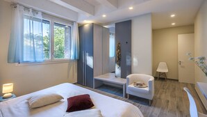 Una habitación de hotel moderna con una cama grande, un área de descanso con una silla, un escritorio y un espejo.