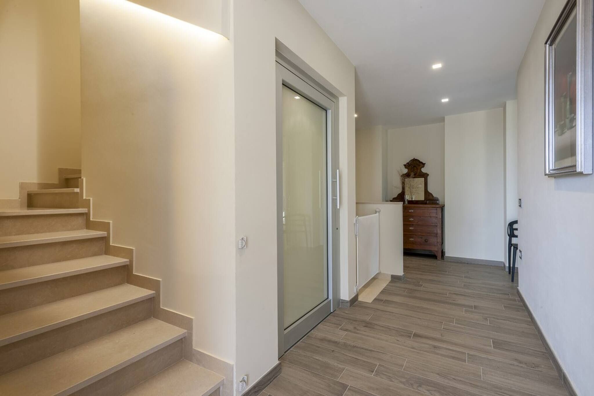 A hallway with a staircase, a sliding glass door, a radiator, and a wooden cabinet.