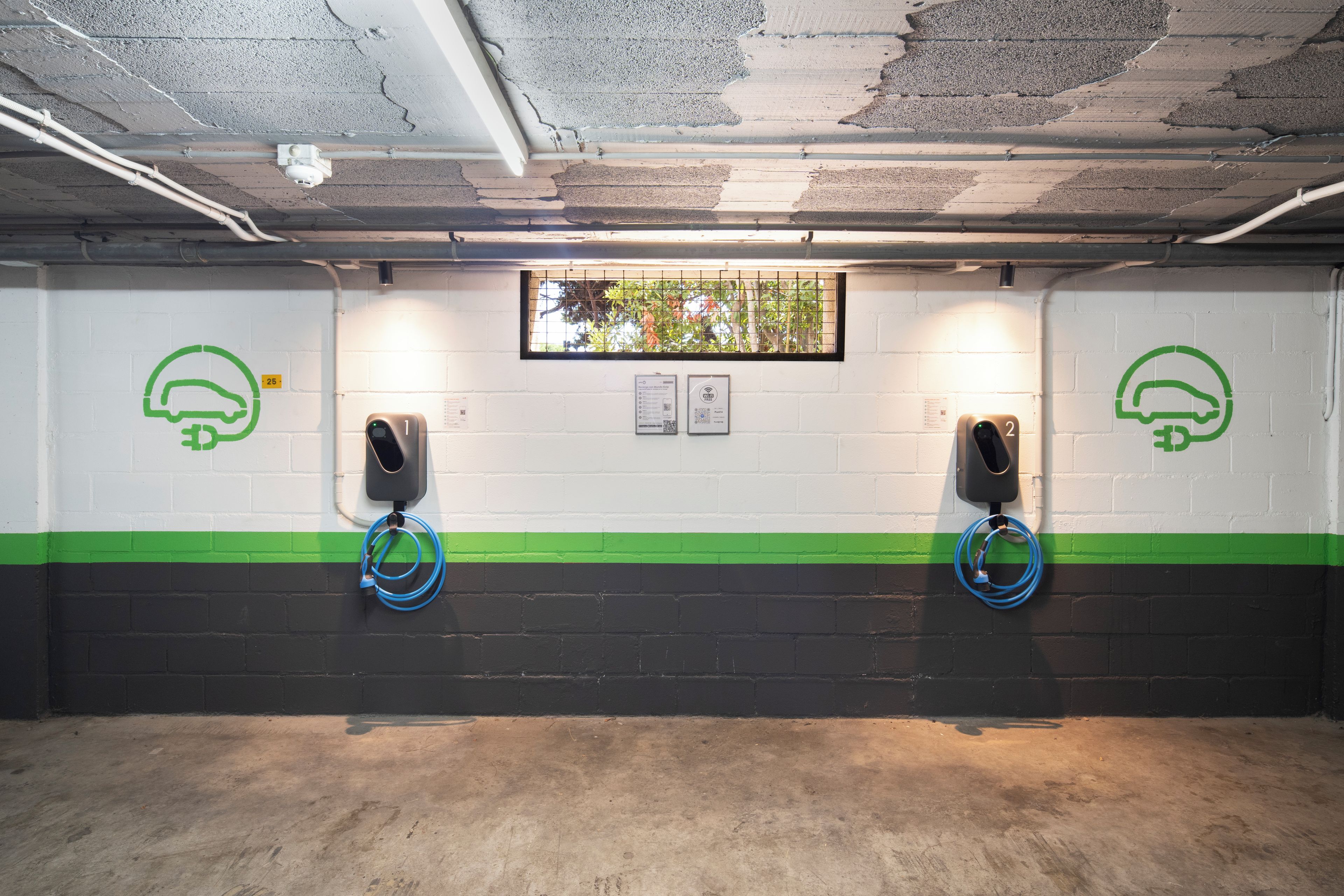Un parcheggio con due stazioni di ricarica per veicoli elettrici, ognuna contrassegnata da un numero e un'icona verde.