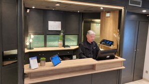 Un comptoir d’accueil doté d’un écran numérique, d’un calendrier et d’une plante.