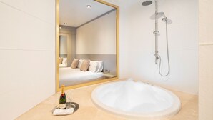 Un baño moderno con un espejo grande, una bañera y una ducha.