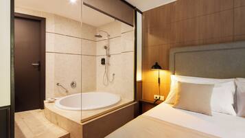 Una habitación de hotel moderna con una cama grande, una zona de ducha separada y una bañera.