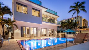 A modern hotel with a rooftop pool, outdoor seating, and palm trees. - Luxury Beach House for Families - Private Pool, Rooftop & Ocean Views (Fort Lauderdale)