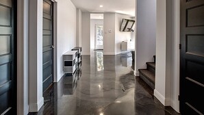 A modern hallway with glossy black floors, white walls, and dark wooden doors.