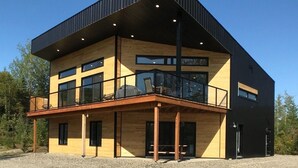 A modern two-story building with a flat roof, large windows, and a balcony.