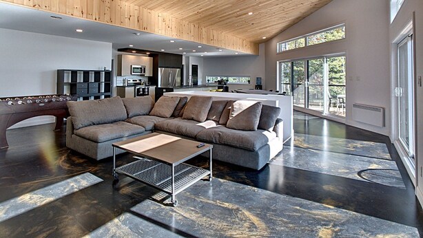 A spacious living area with a modern kitchen in the background, a large sectional sofa, and a coffee table.