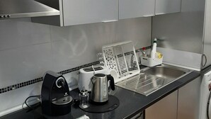 Uma cozinha moderna com eletrodomésticos de aço inoxidável, chaleira, torradeira e cafeteira no balcão.