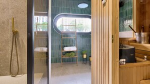 A modern bathroom with a glass-enclosed shower, a wooden vanity, a sauna, and a view of the outside.