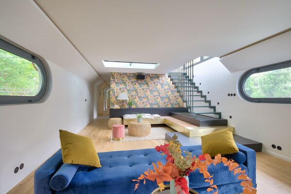 Un intérieur moderne avec un canapé bleu, un escalier et un mur orné de motifs.