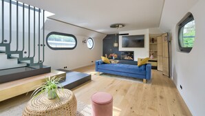 A modern interior with a blue sofa, wooden flooring, and a staircase with glass railings.