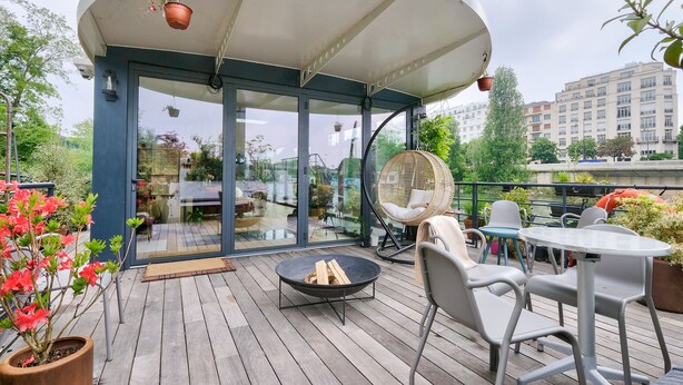 A covered outdoor seating area with a glass door, a round table, and a fire pit.