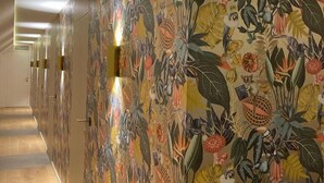 A hallway with patterned wallpaper and recessed lighting.