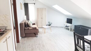 A modern apartment with a loft-style ceiling, a sofa, a small table, a TV, and a kitchen area. - Spectacular View only 5 min. walk from beach, restaurants, attractions and more! (Korčula)