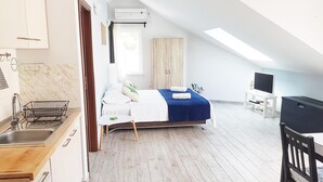 A modern, well-lit room with a bed, a TV, and a dining area. - Spectacular View only 5 min. walk from beach, restaurants, attractions and more! (Korčula)