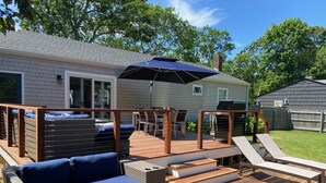 Une terrasse avec un canapé en osier, un barbecue et un banc en bois.