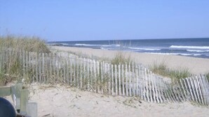 Une plage avec une clôture en bois et des vagues de l’océan.