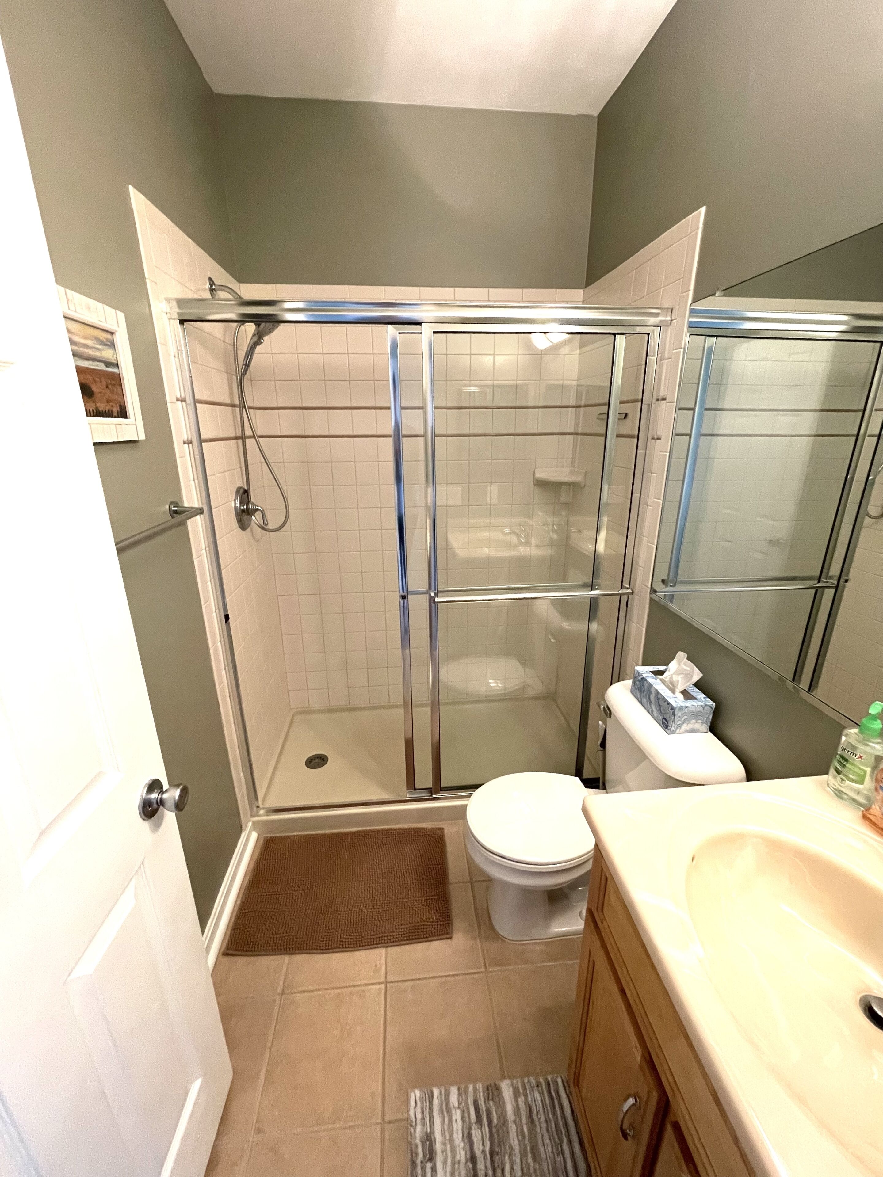 A bathroom with a glass-enclosed shower, a toilet, and a sink.