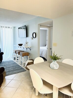 Enjoy meals at the dining table with four chairs, surrounded by a small side table and a framed picture.