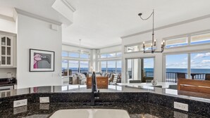 Een ruime keuken met een groot kookeiland, uitzicht op de oceaan en een balkon met zitplaatsen.