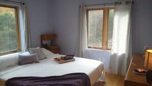 A bedroom with a bed, bedside tables, a nightstand, a window, and a lamp. - Large relaxing house in 25 acres of private woods with lake access. (Spencer)