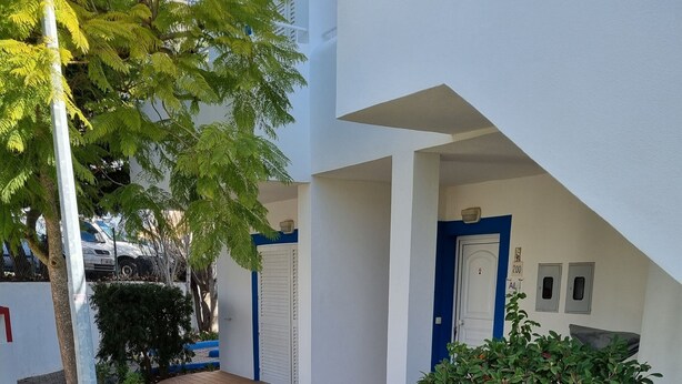 Un patio empedrado con baldosas hexagonales, una puerta de metal y un borde pintado de azul.