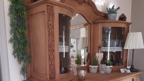 Un mueble de madera con puertas de cristal, plantas decorativas y una lámpara.