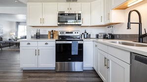 A modern kitchen with white cabinetry, stainless steel appliances, and a central island. - Old Town Scottsdale | Heated Pool & Putting Green (Scottsdale)