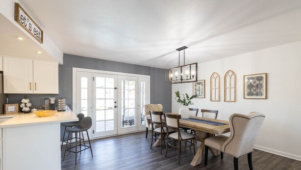 A modern kitchen with white cabinets, a dining area with a wooden table and chairs, and a large window with a view. - Old Town Scottsdale | Heated Pool & Putting Green (Scottsdale)