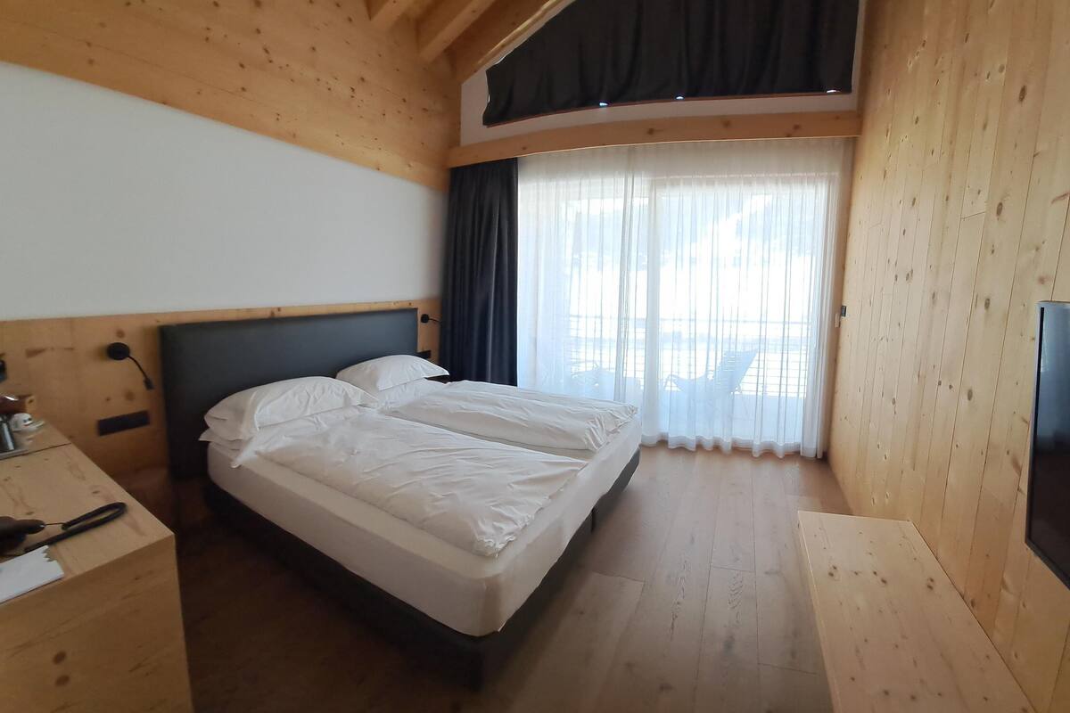 Un dormitorio con una cama, un escritorio y un televisor.